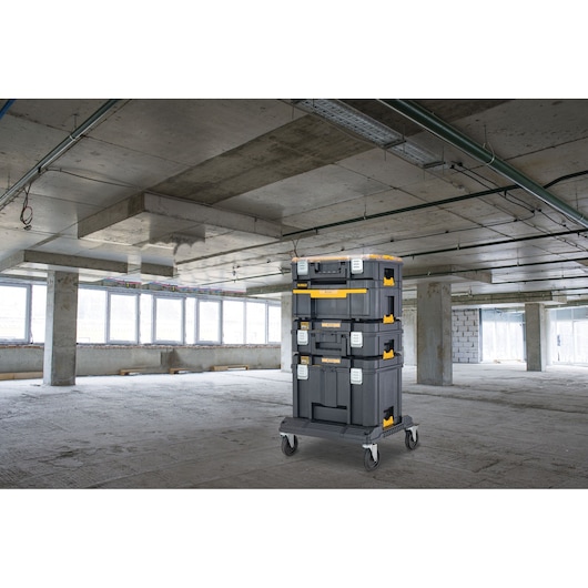 DEWALT tool storage stack on wheels in an unfinished industrial building with concrete floors and ceiling.