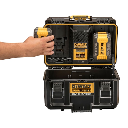 DEWALT ToughSystem 2.0 black toolbox with charger, opened, hand placing battery inside.