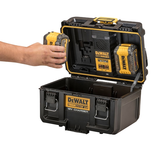 DEWALT ToughSystem 2.0 box with 18V charger, hand placing a battery into charging slot, open case displayed.