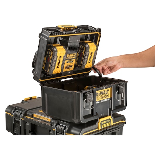 DEWALT ToughSystem 2.0 toolbox with open lid, showing battery charger and batteries, hand holding a strap.