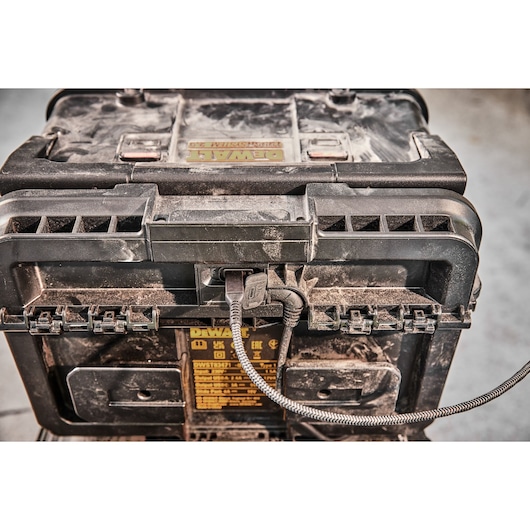 Close-up of a dusty DEWALT tool case DWST83471 with a cable plugged into its port.