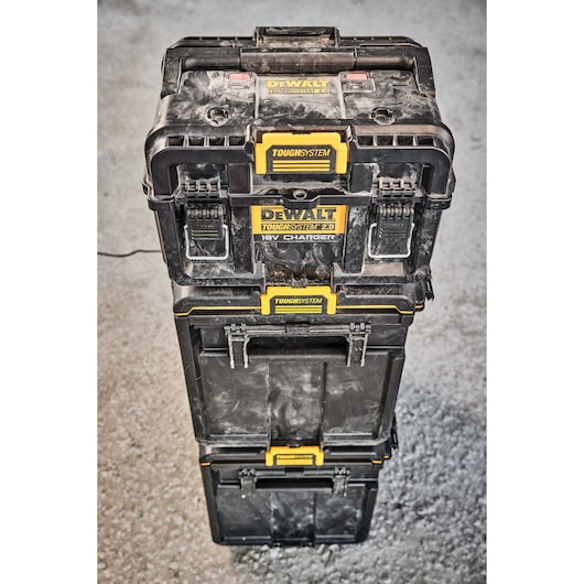 Stacked DEWALT ToughSystem toolboxes with yellow locks on a concrete floor, used for tool storage and charging.