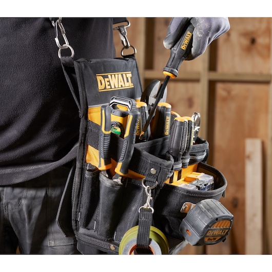 DEWALT tool belt with assorted tools and tape measure in carpenter's workshop.