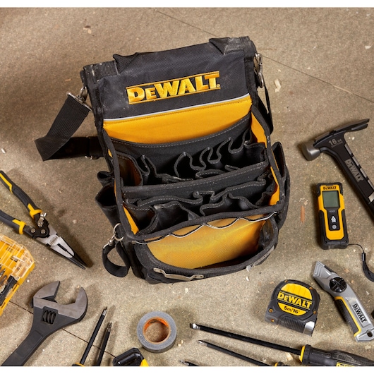 DEWALT tool bag with compartments, surrounded by hand tools and accessories on a workshop floor.