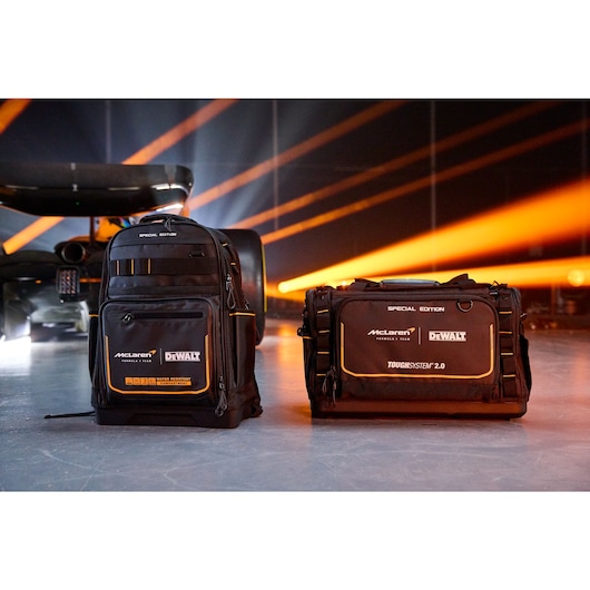 DEWALT special edition backpack and tool bag with McLaren logo, black and orange, on a studio floor with lights.