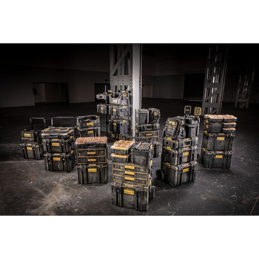Multiple DEWALT black and yellow storage and tool boxes are arranged in stacks in a large indoor space, highlighting various sizes and configurations.