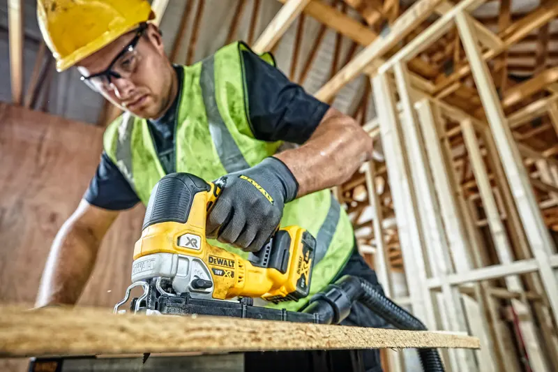 Scie sauteuse DEWALT DCS334P2 utilisée pour couper du bois sur chantier par un ouvrier équipé.
