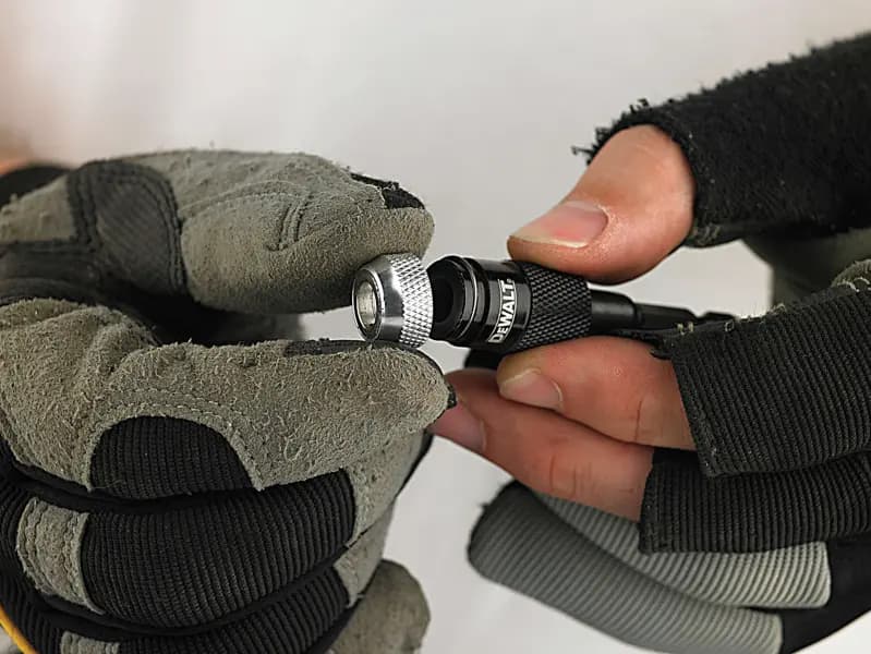 Mains gantées tenant et ajustant un porte-embout DEWALT.