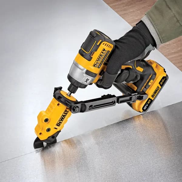 Outil DEWALT équipé coupe une tôle, utilisé par une main gantée.