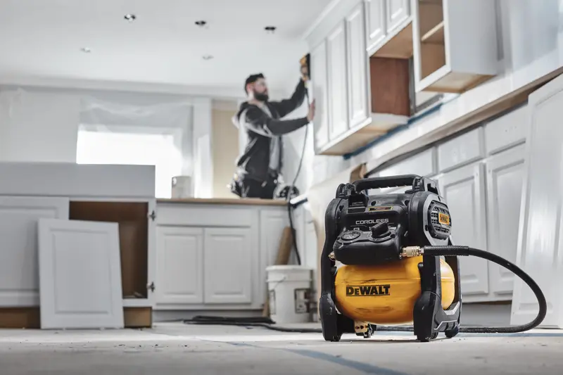 Compresseur sans fil DEWALT lors d'une rénovation de cuisine avec un ouvrier utilisant des outils.