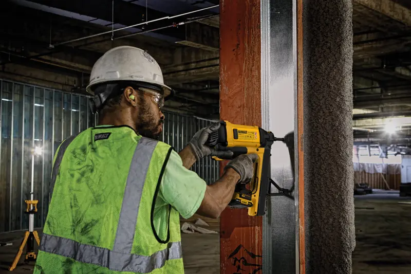 Ouvrier utilisant DEWALT, DGN845D1-QW et DGN845D1, sur cadre métal sur chantier.
