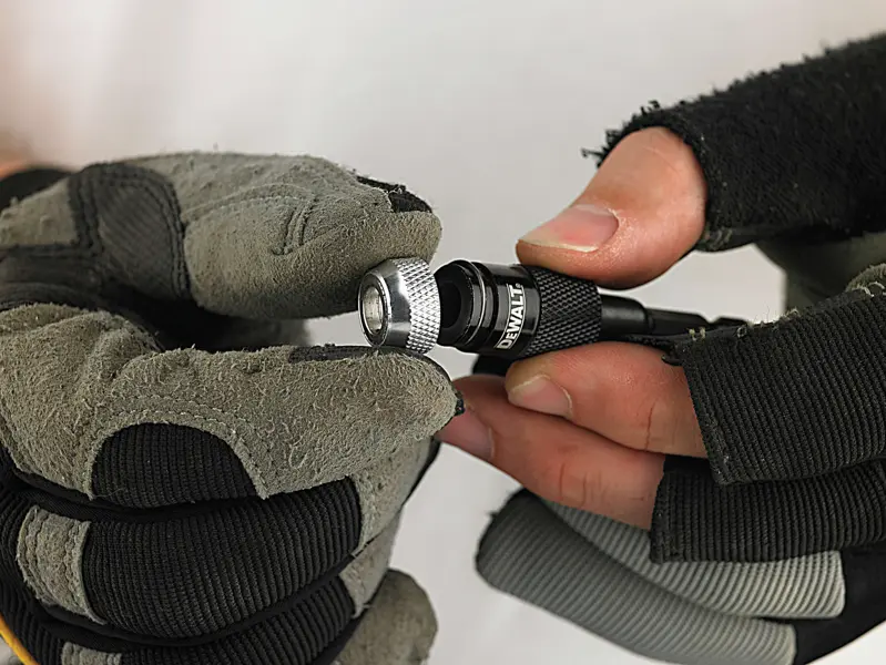Mains gantées tenant et ajustant un porte-embout DEWALT.